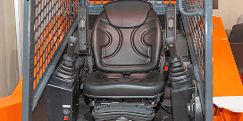 Operator seat and control joysticks inside a forklift cab with protective safety cage.