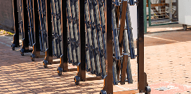 Foldable metal barriers on wheels arranged in a row for crowd control or temporary access restriction.