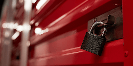 Close-up of a padlock securing a red metal cabinet or toolbox, symbolizing safety and equipment security.