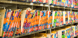 Rows of folders sitting between vertical slots on a high-density shelving unit in an office